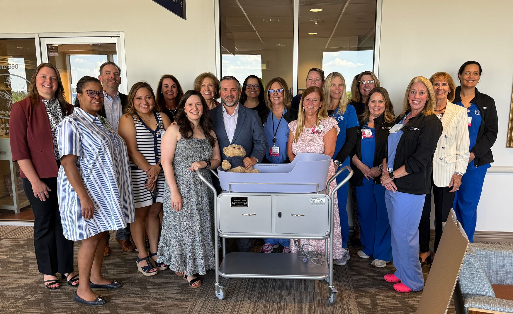 Group of people standing indoors behind a printer, posing together and smiling.