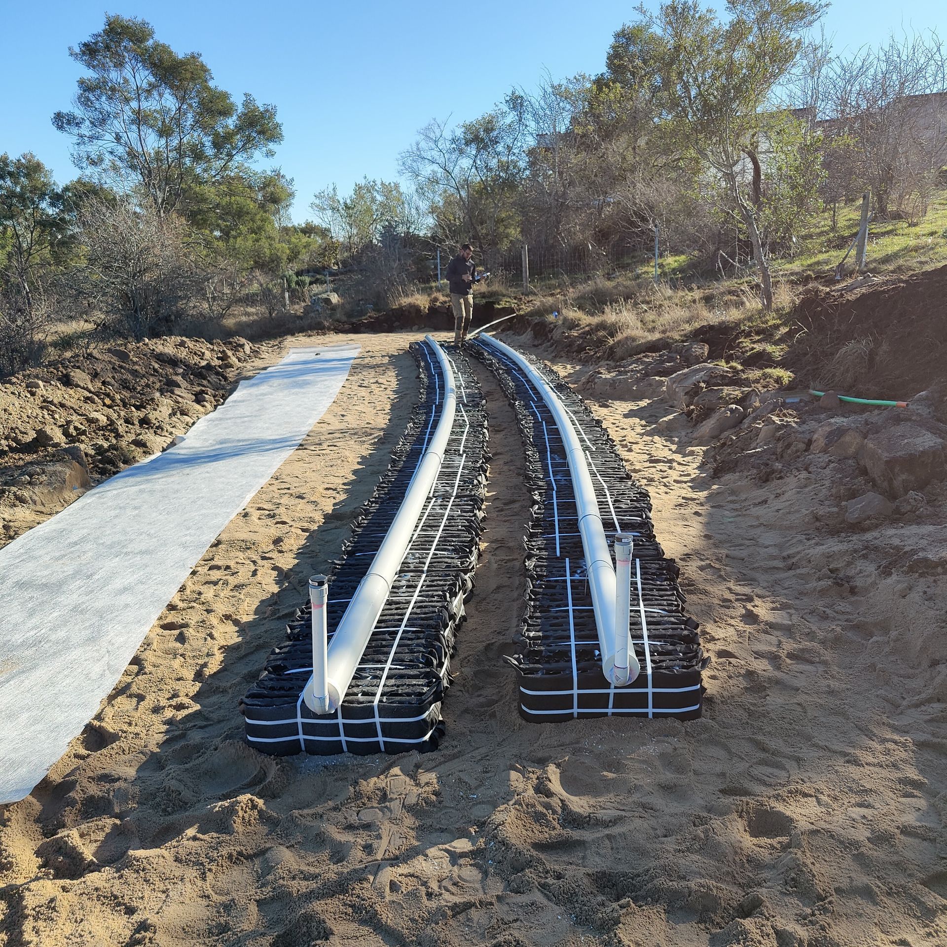 A couple of white pipes are laying in the dirt