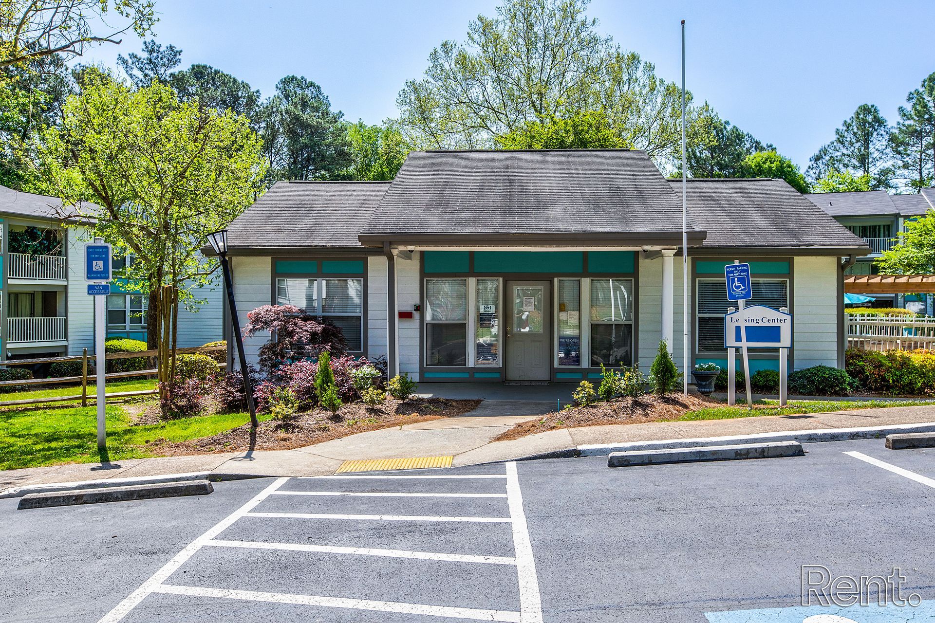 Small building entrance with glass doors, driveway, and accessible parking signs in front.