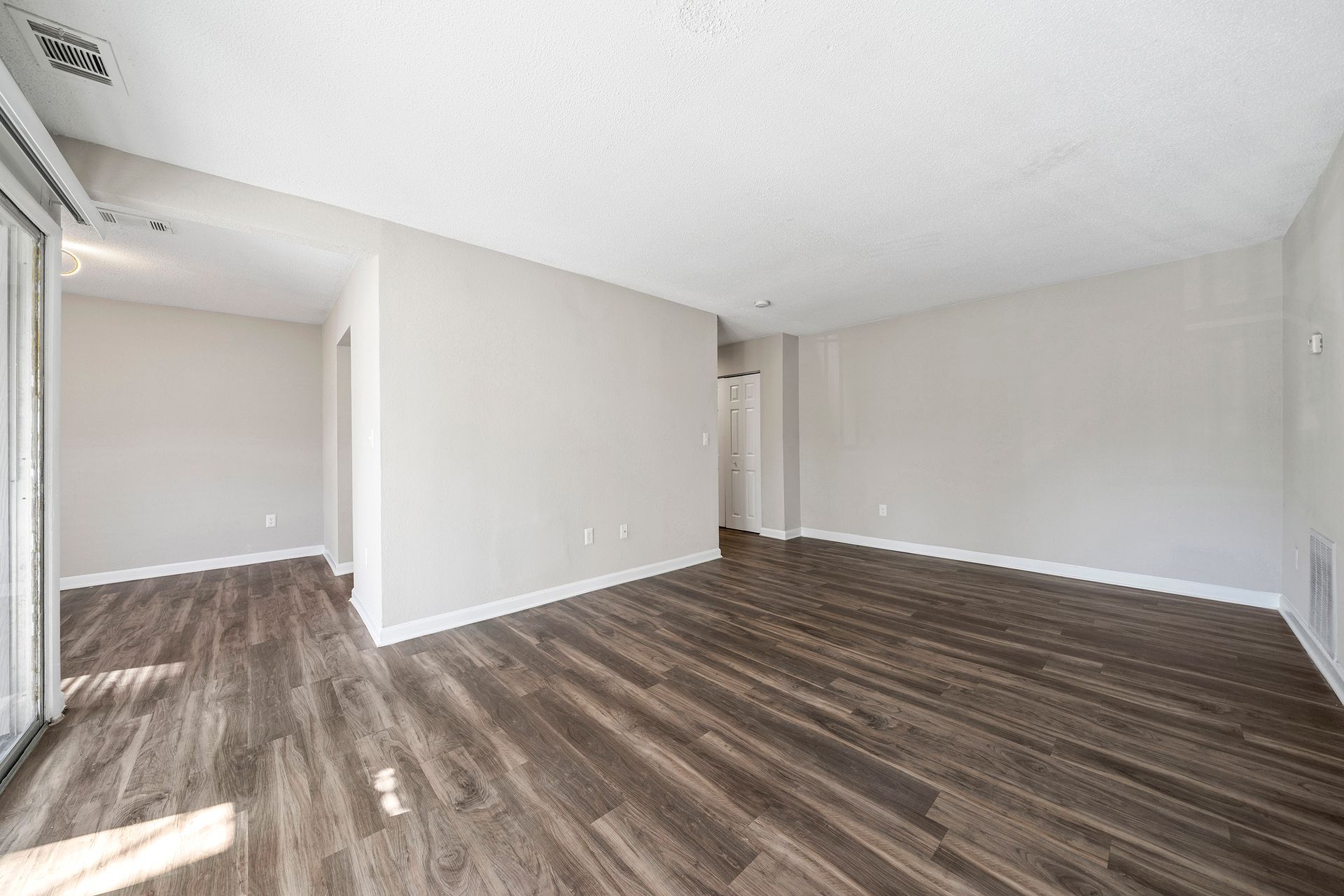 Empty modern room with gray walls and wood-look flooring, bright with natural light