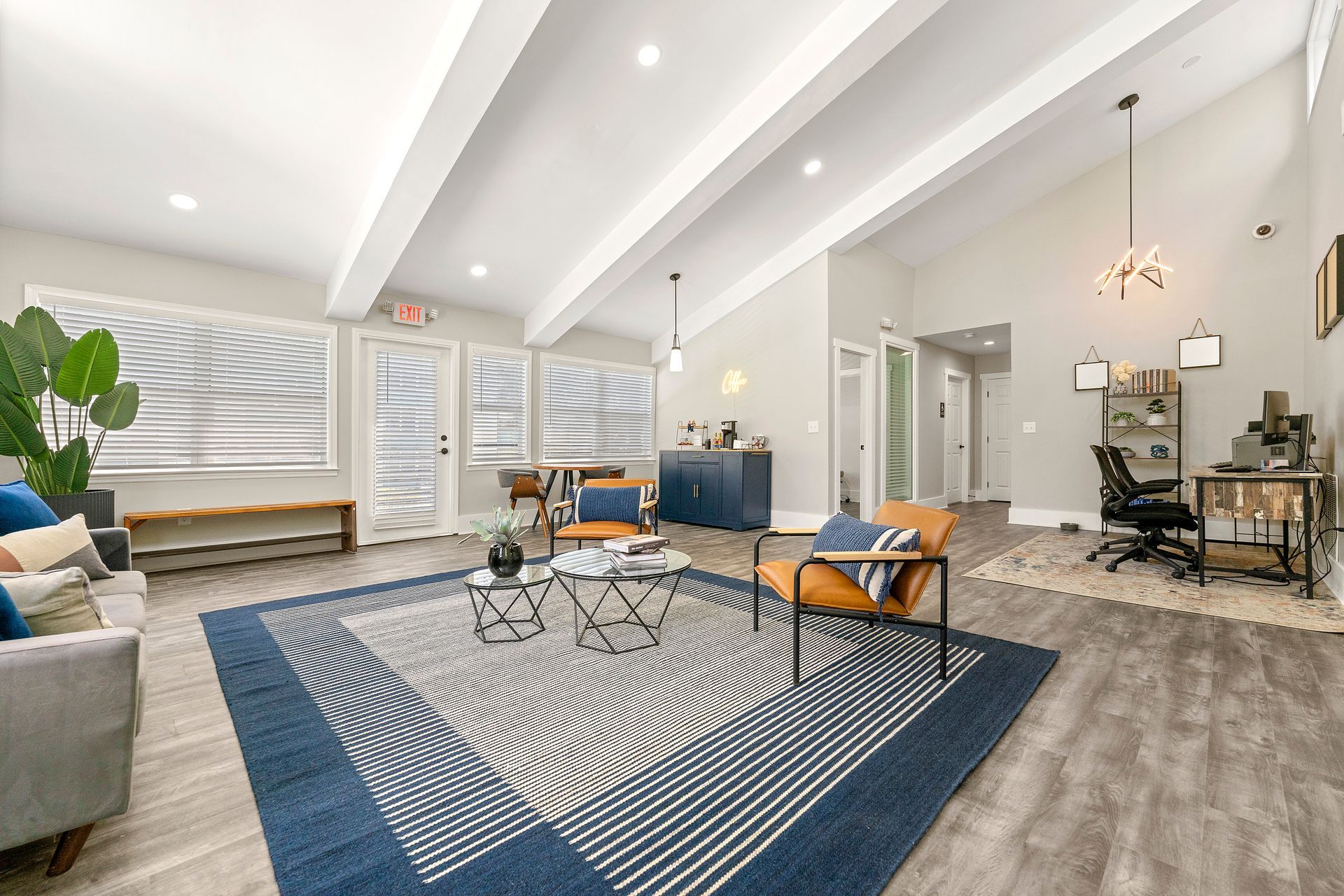 Bright modern living room with blue rug, white sectional, coffee table, and dining area beyond