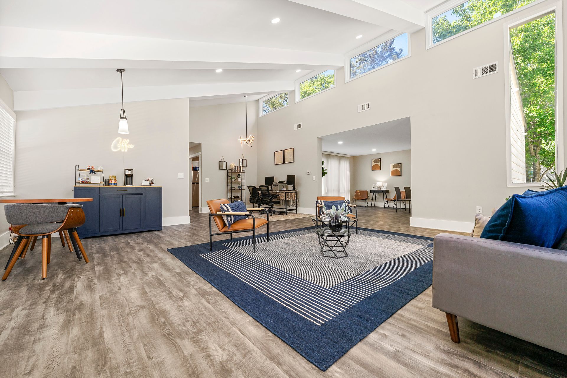 Bright open-plan living room with blue kitchen island, large rug, gray sofa, and fireplace wall art