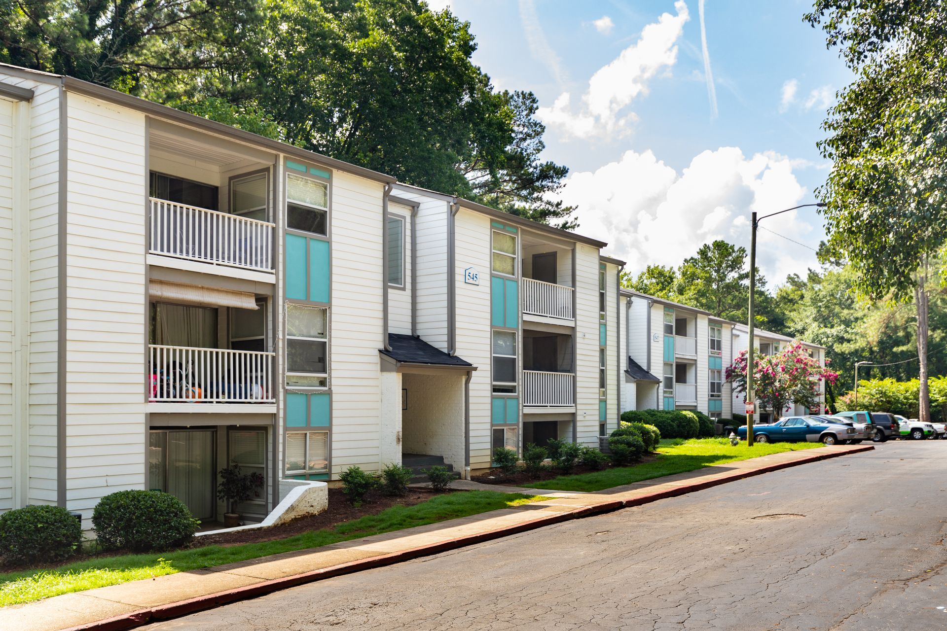 Apartment buildings beside a tree-lined street on a sunny day
