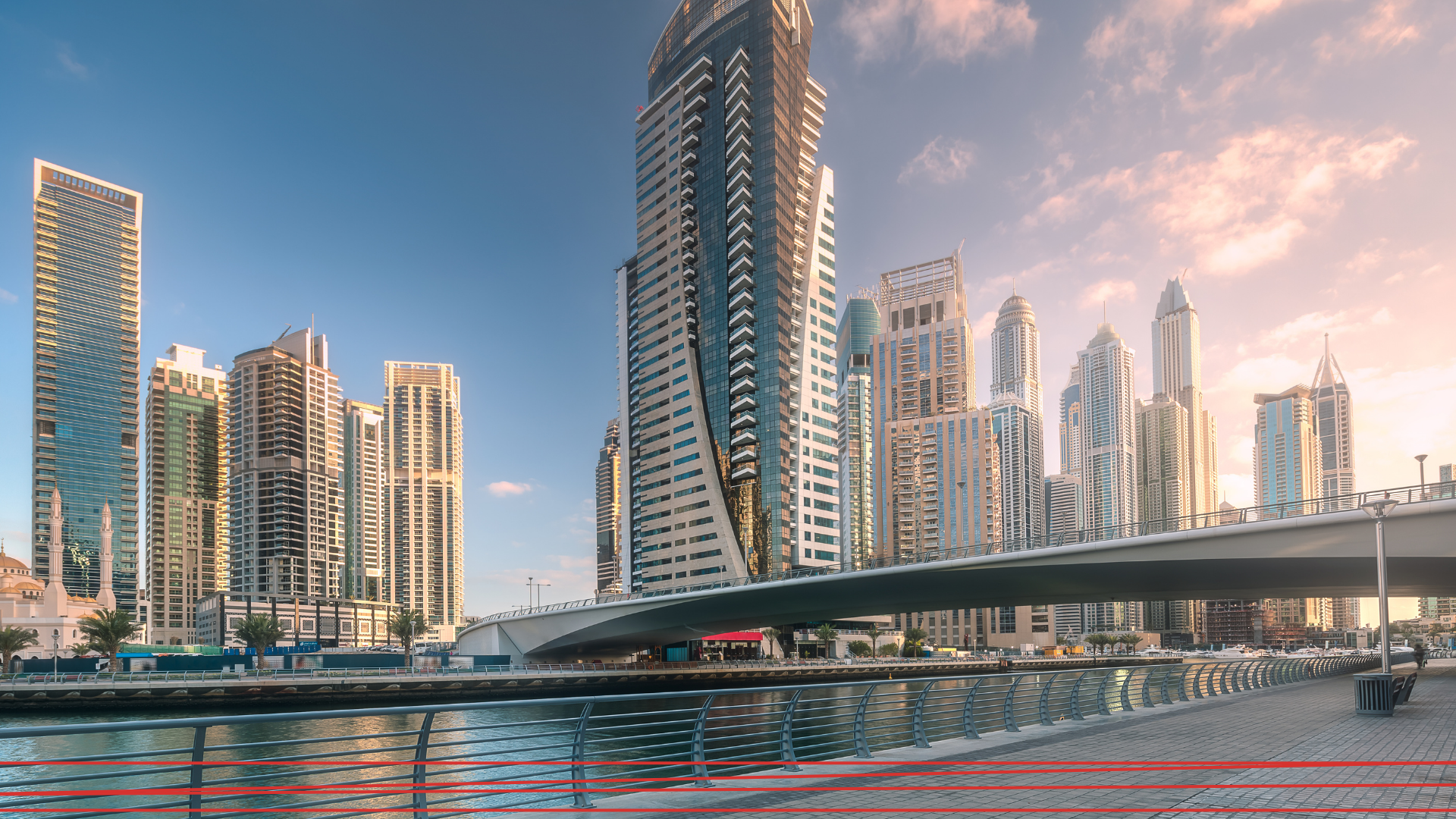 Una veduta del lungomare di Dubai Marina, con i grattacieli sullo sfondo, immortalata al tramonto e un ponte che attraversa il canale.