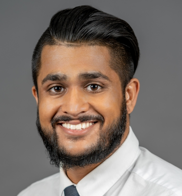 Professional profile photo of Dr. Sunny Patel, MD, Pediatrician wearing a white dress shirt and a dark tie, photographed against a plain dark gray background.