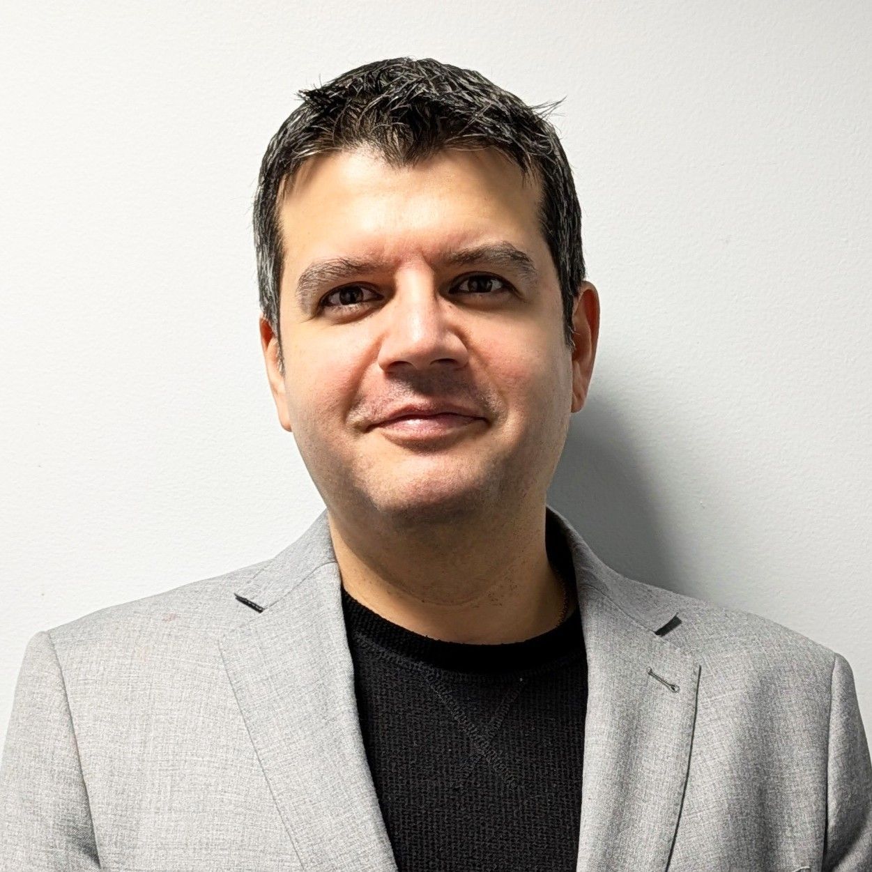 Head‑and‑shoulders profile photo of Dr. Johnny Mendoza, MD wearing a light gray blazer over a dark top, photographed against a plain light‑colored background.