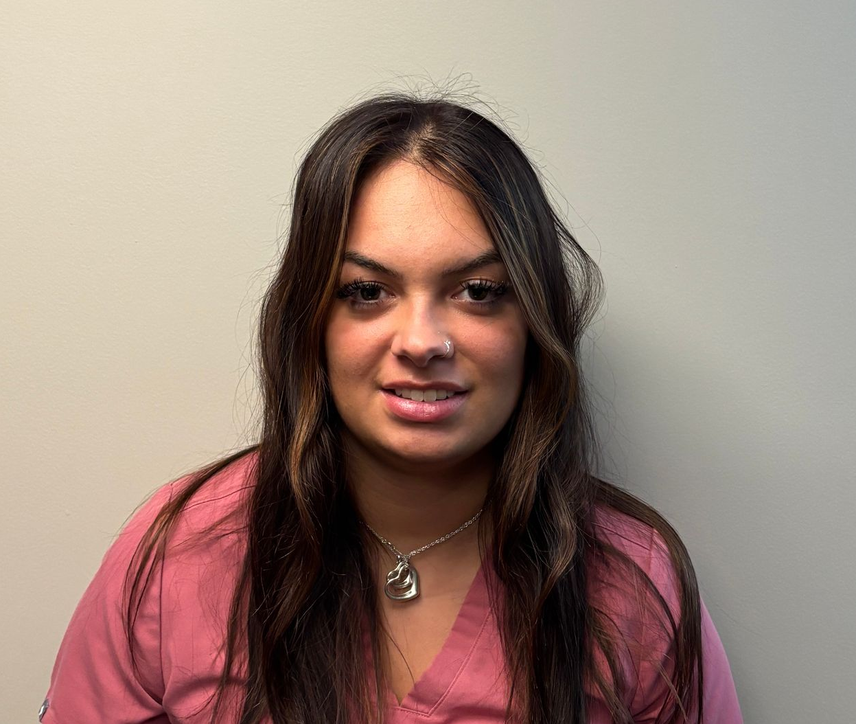 Profile photo of Kayla Thompson, Medical Assistant wearing a pink scrub top and a necklace, photographed against a plain light colored background.