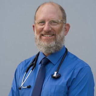 Picture of Dr. Andrew Williams.  Wearing a blue shirt and tie with Stethoscope hung around his neck. 