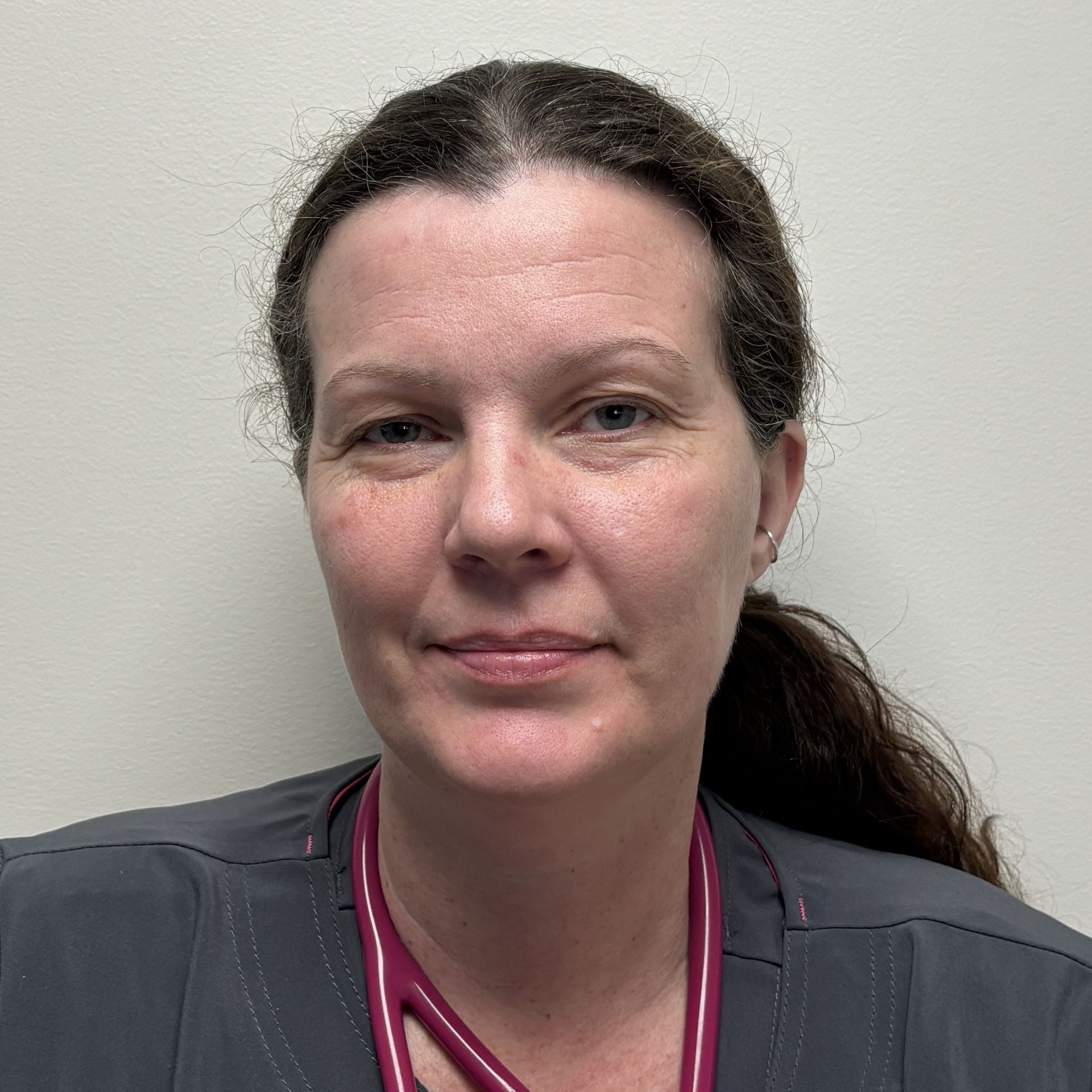 Professional profile photo of Renata Cronk, LPN wearing a gray scrub top and a stethoscope, photographed against a plain light-colored background.