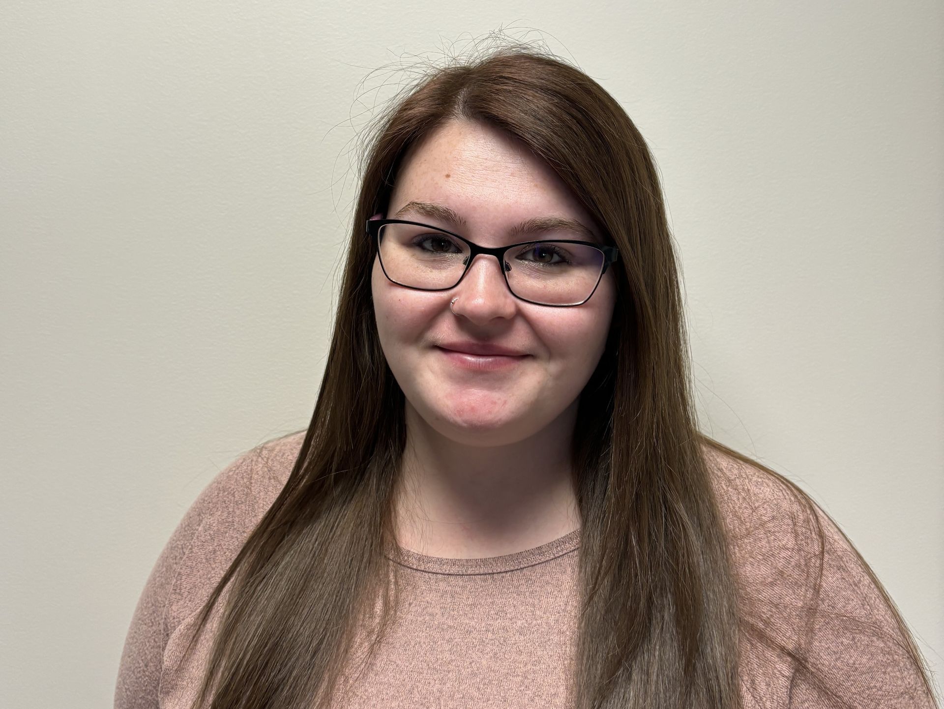 Professional profile photo of Kristina Whitmarsh, Care Coordinator wearing glasses and a light pink long-sleeved top, photographed against a plain light-colored background.