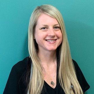 Professional profile photo of Melissa Benardot, Family Nurse Practitioner with long light-colored hair wearing a black top and a necklace, photographed against a plain teal-colored background.