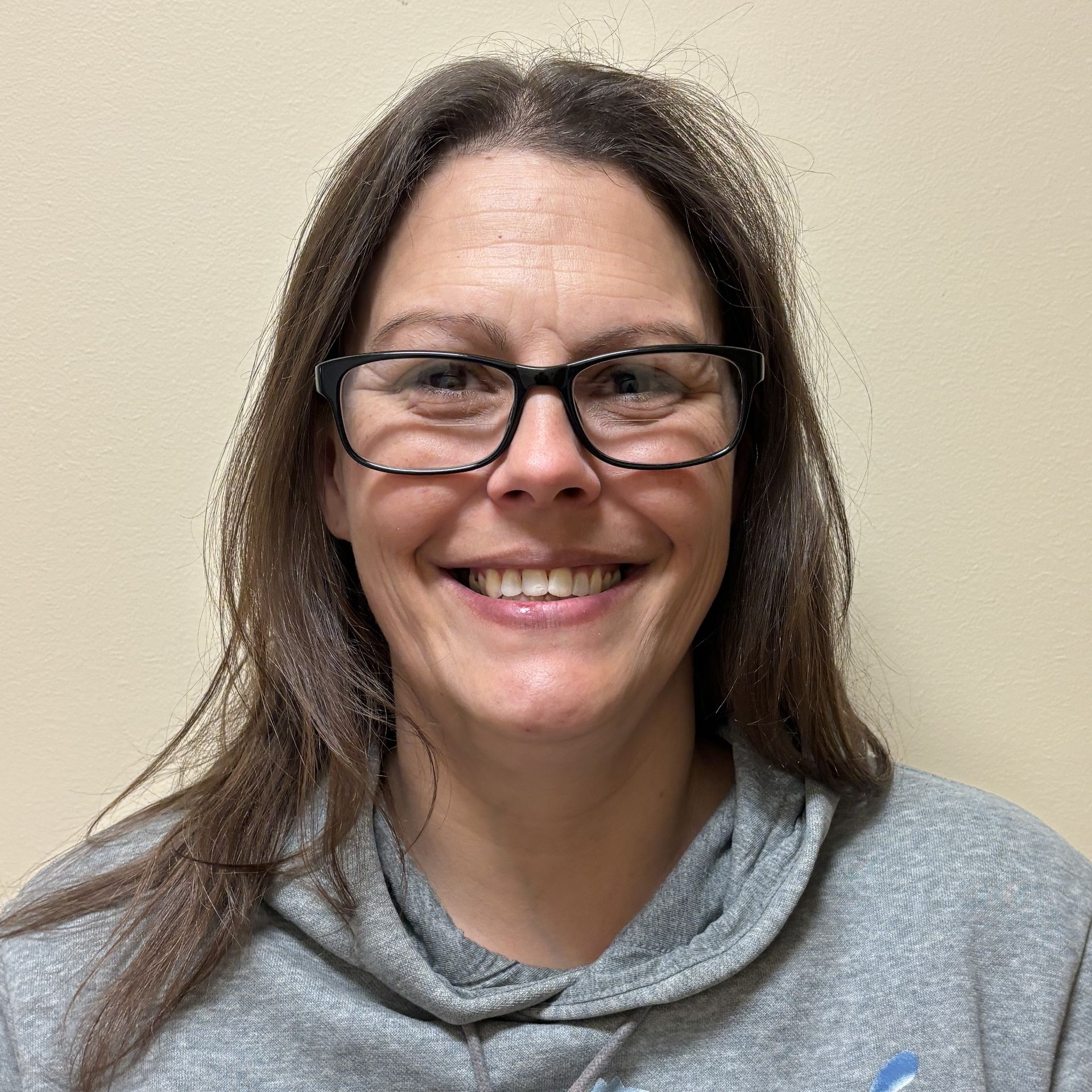 Professional profile photo of Amanda Rockhill, Medical Assistant wearing glasses and a gray hooded sweatshirt, photographed against a plain light-colored background