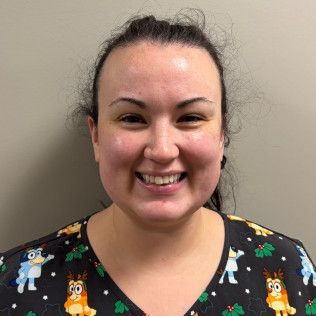 Profile photo of Mary Henry, RN wearing a dark scrub top with a colorful patterned design, photographed against a plain light-colored background.  She is part of the Pediatric Care Team.