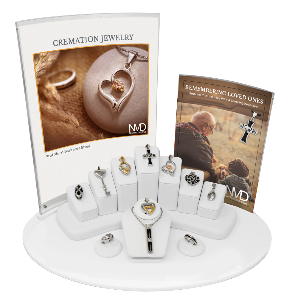 A display set of cremation jewelry necklaces and rings on white stands, featuring an informational sign and brochure.