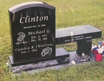 A black granite headstone with a bench attachment, inscribed with the Clinton family name, dates, and icons in a cemetery.