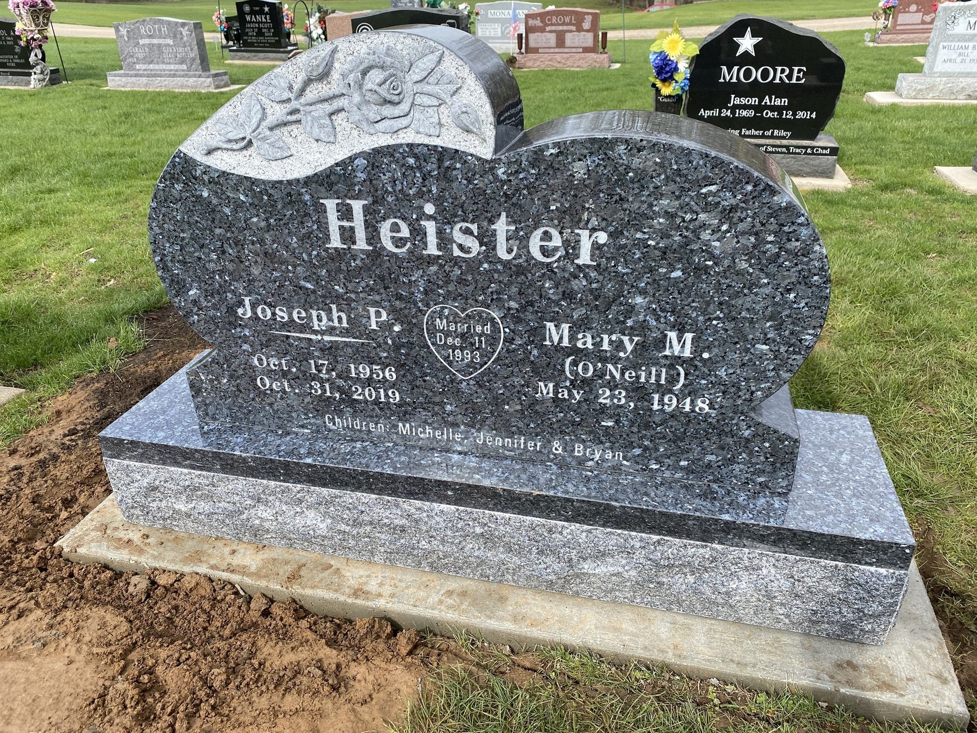 A dark blue granite heart-shaped tombstone for the Heister family, set in a grassy cemetery.