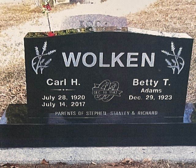 A black granite headstone for Carl H. (1920–2017) and Betty T. Wolken, marked with their wedding date and children's names.