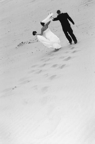 Bride and groom holding hands while walking uphill on a snowy slope