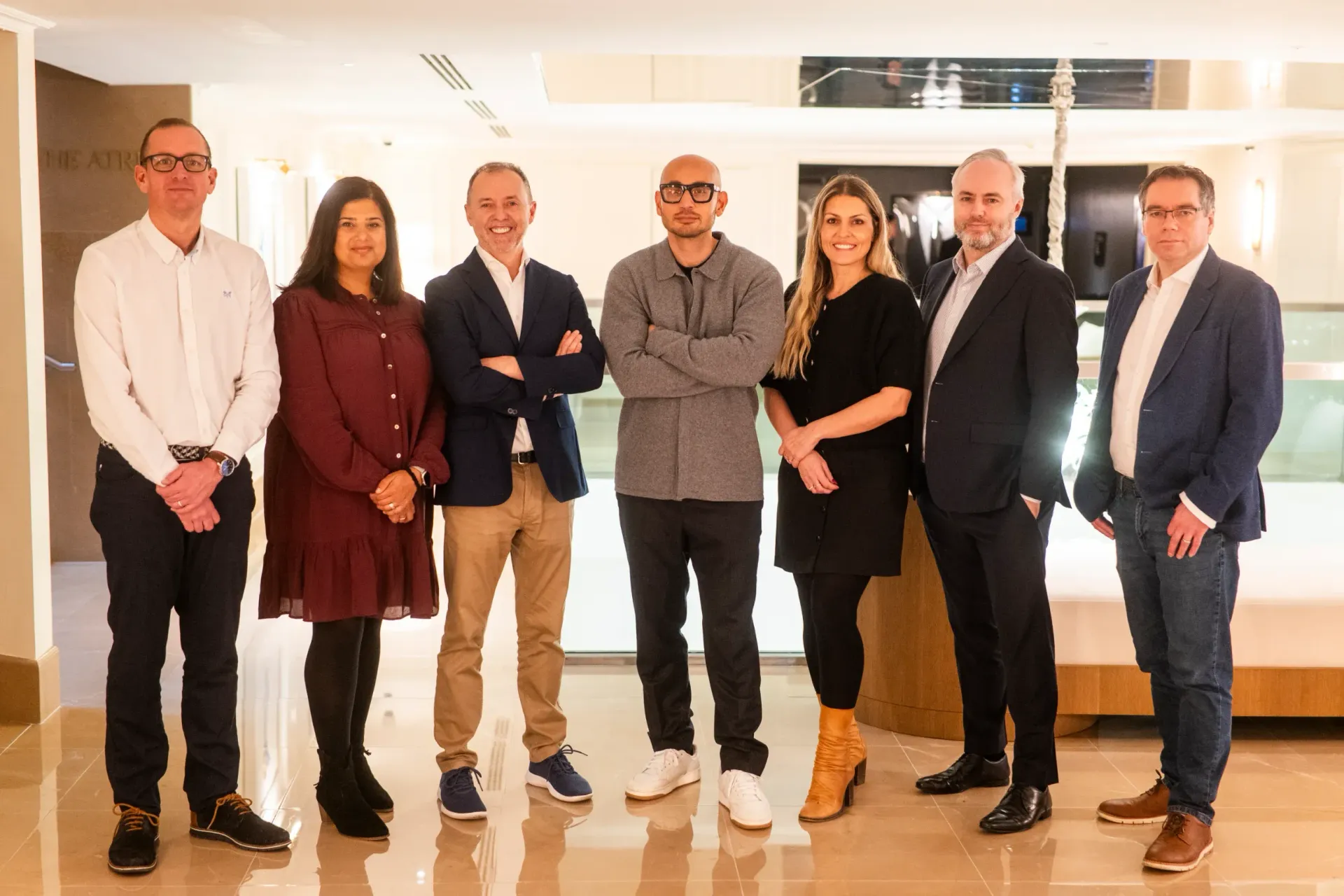 Seven people standing in a bright lobby, posing for a group photo.