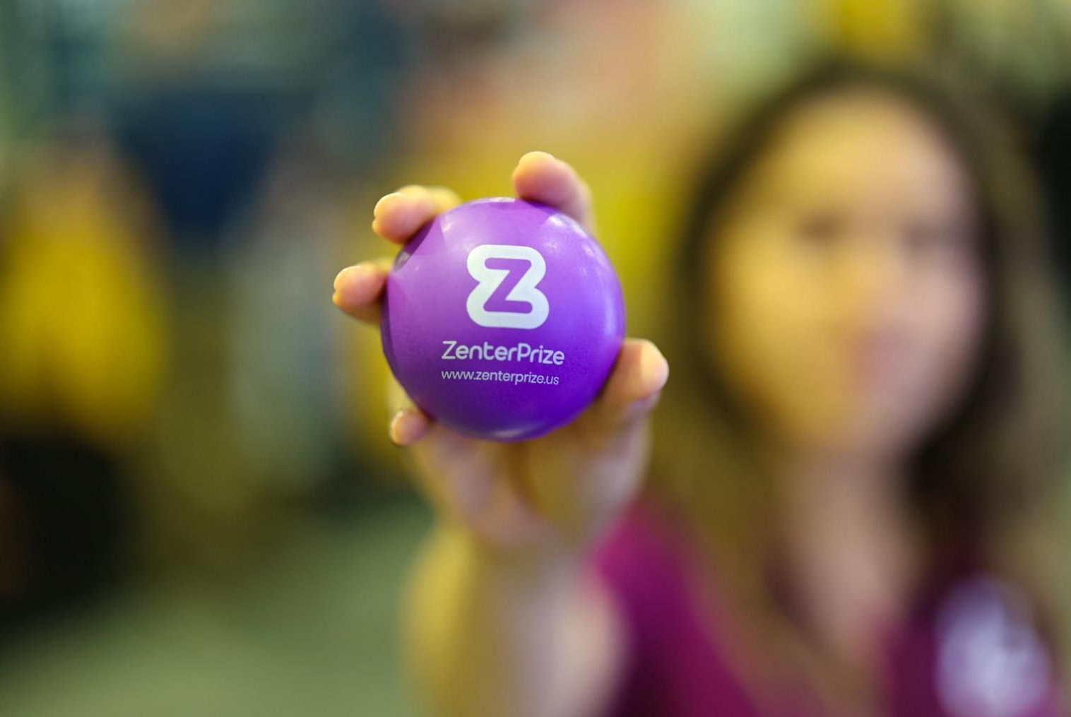 Hand holding a purple ZenBusiness ball with a white Z logo, person blurred in background