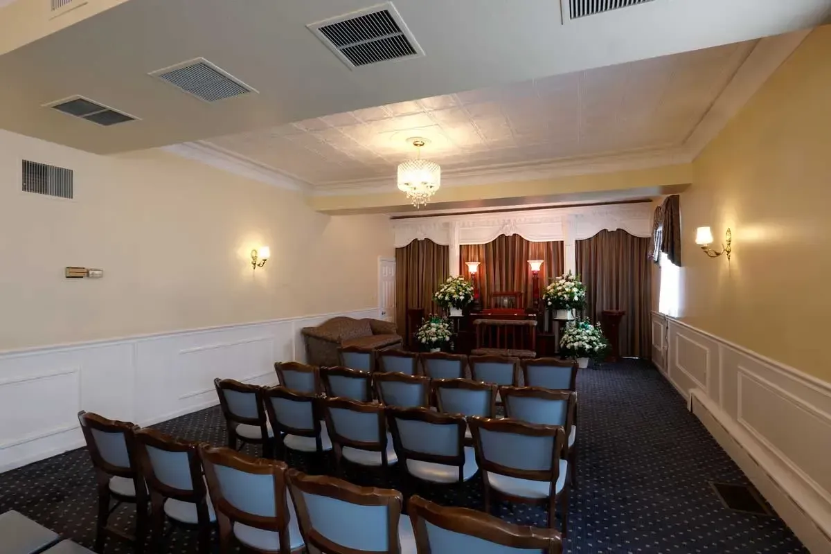 Empty conference room with rows of chairs facing a small stage and floral arrangement