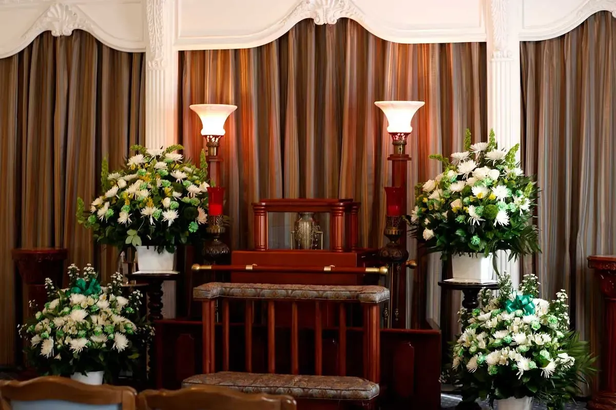 Decorated funeral altar with flowers, candles, and draped curtains in a chapel