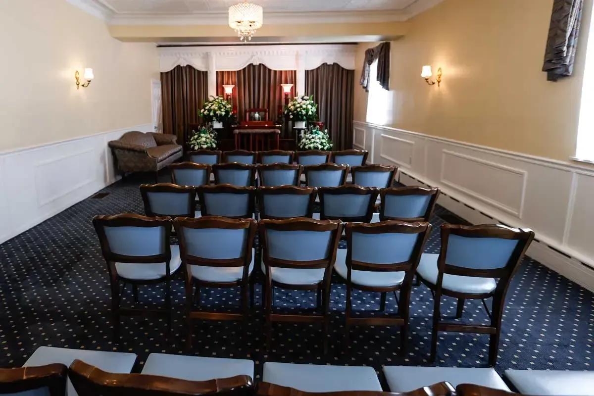 Empty chapel with rows of blue chairs facing a flower-decorated altar.