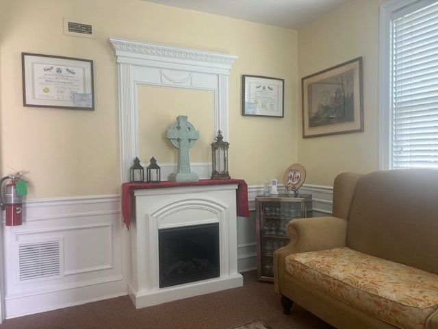 Bright living room with white fireplace, framed art, and a tan sofa against beige walls