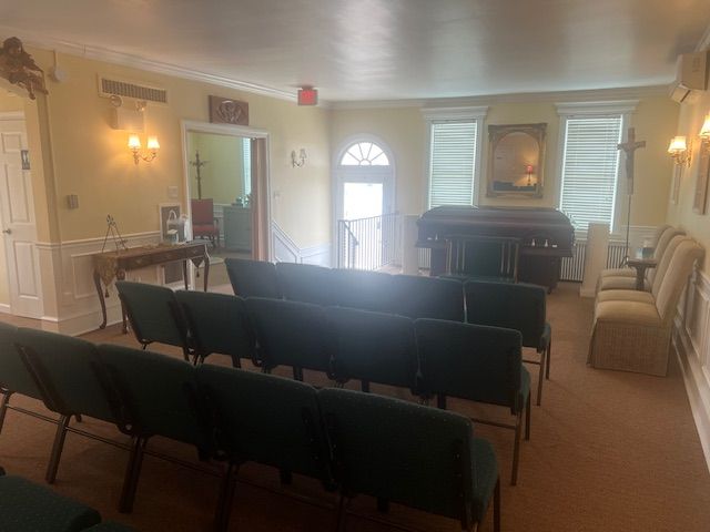 Meeting room with rows of dark chairs, a podium, and a fireplace in a warmly lit hall