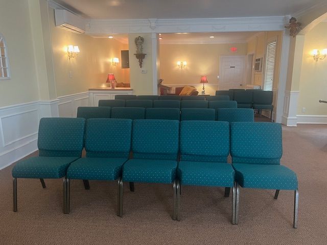 Empty waiting room with teal chairs, beige walls, and soft wall lighting.