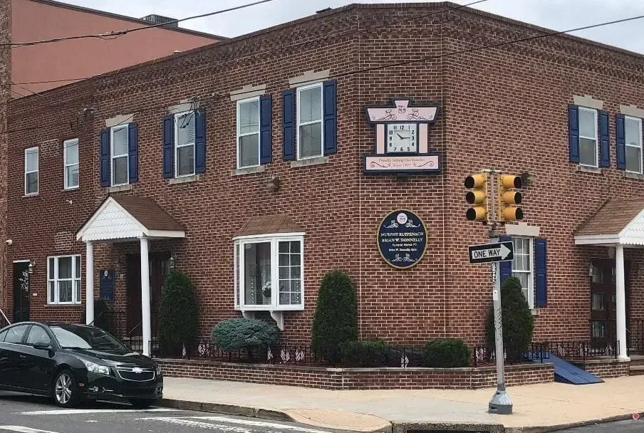 Brick corner building with blue-trim windows, signs, and a traffic light at the street intersection