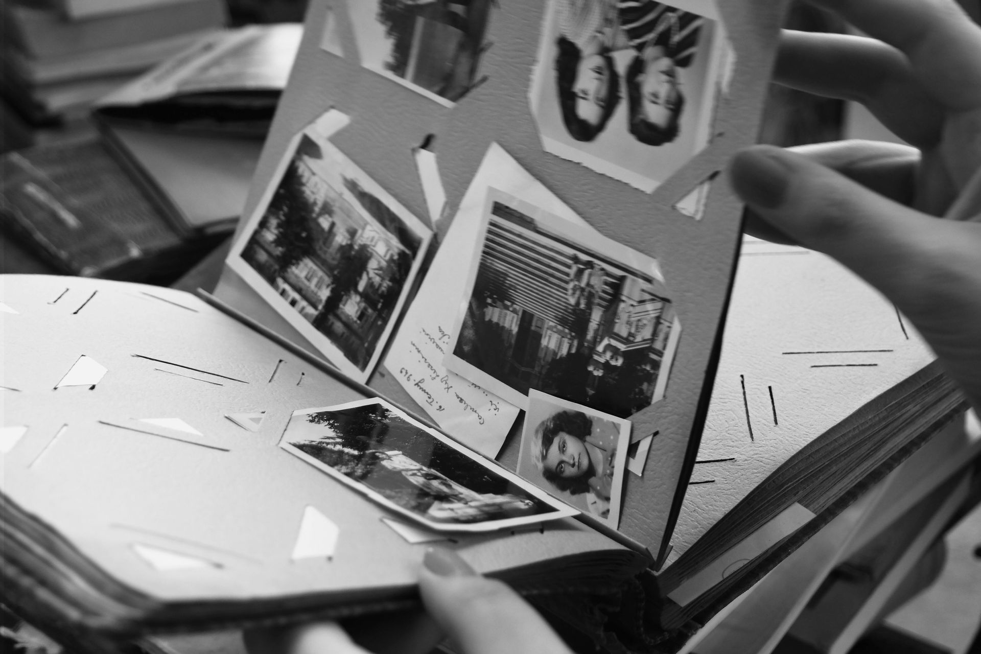 Hands holding an open pop-up photo card with multiple pictures inside on a table