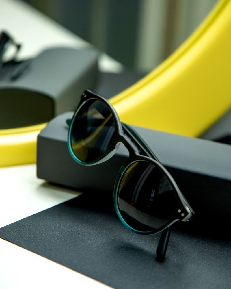 Black sunglasses on a black case with a yellow curved background