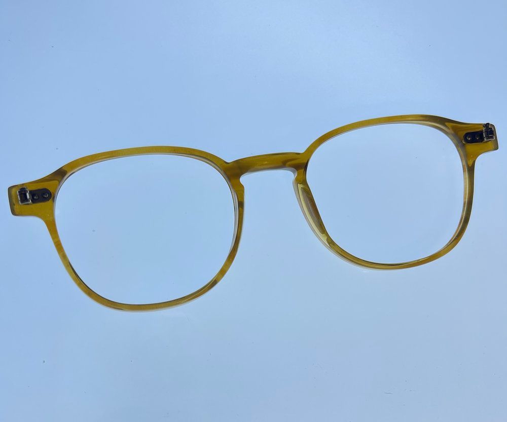 Yellow round eyeglasses with clear lenses on a light blue background