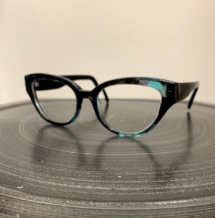 Black cat-eye eyeglasses with blue accents on a gray surface