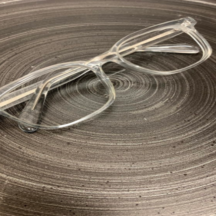Clear eyeglasses resting on a gray, spiral-textured surface