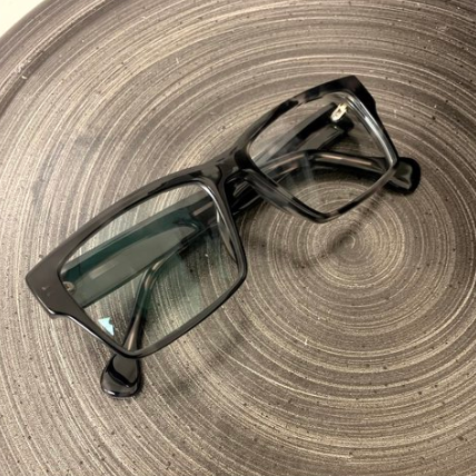 Black rectangular eyeglasses on a gray spiral-patterned surface
