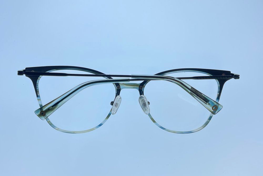 Transparent eyeglasses with a black brow bar on a light blue background