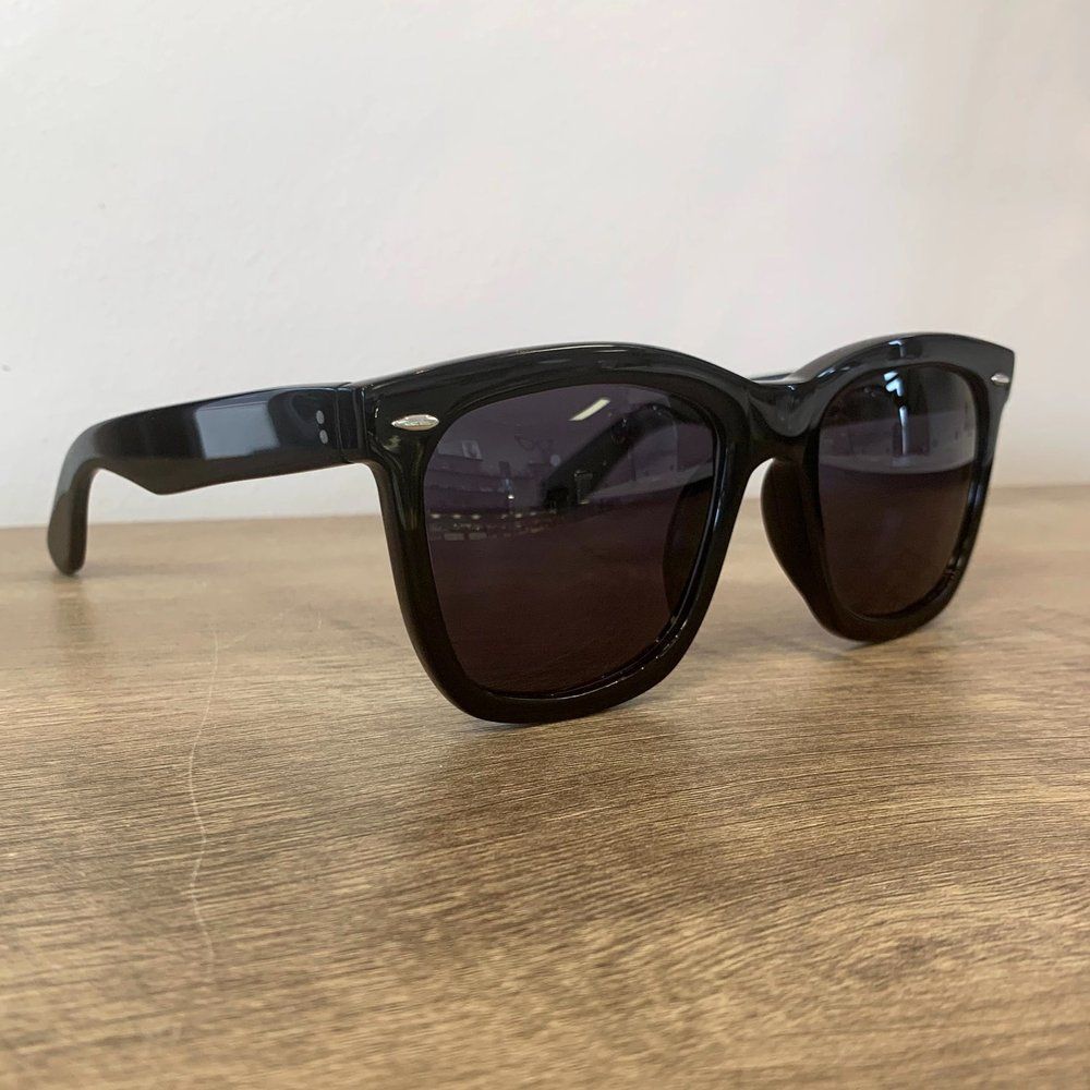 Black sunglasses with dark lenses resting on a wooden surface.