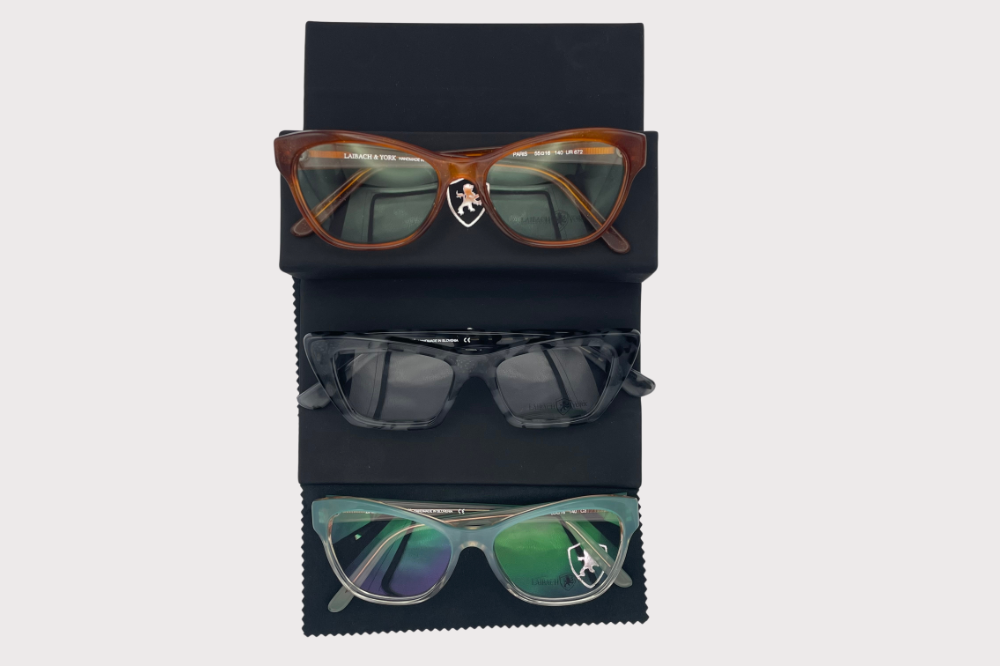 Several eyeglass frames in black, neon yellow, tortoiseshell, and pink on a light background
