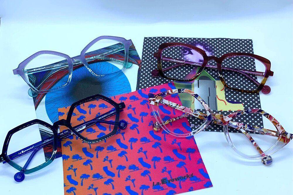 Assorted eyeglasses and colorful patterned cases arranged on a white surface