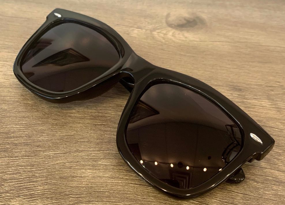 Black sunglasses with dark lenses on a wooden surface
