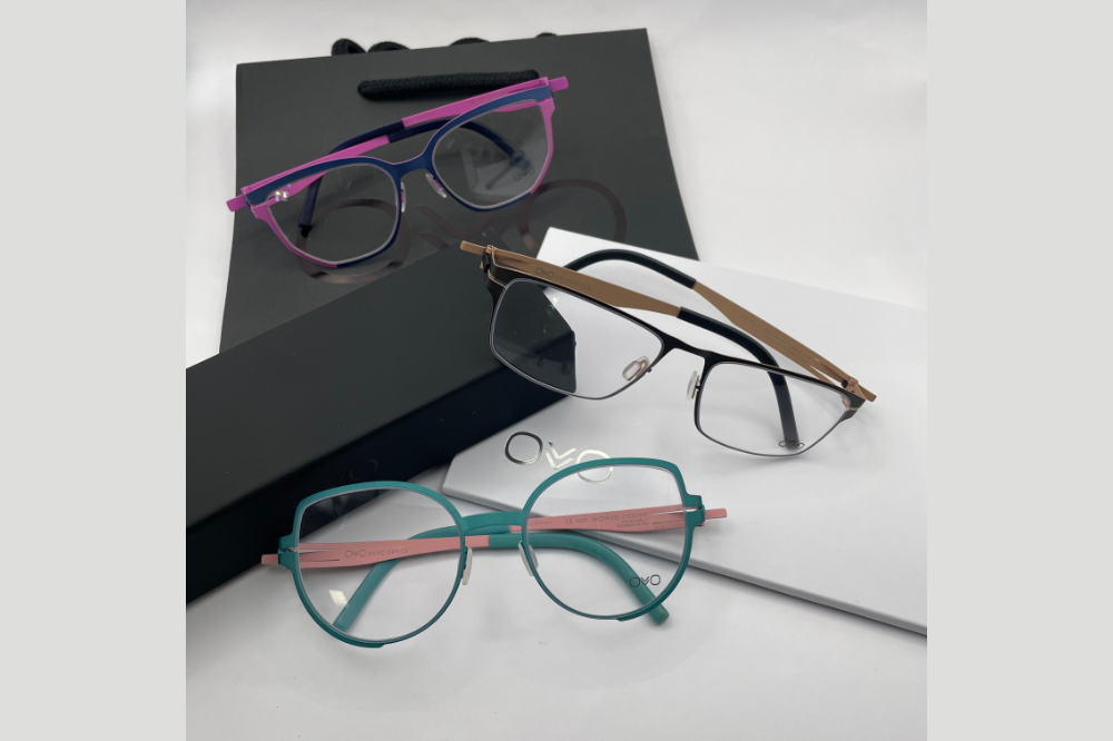 Four eyeglass frames on a blue box against a light blue background