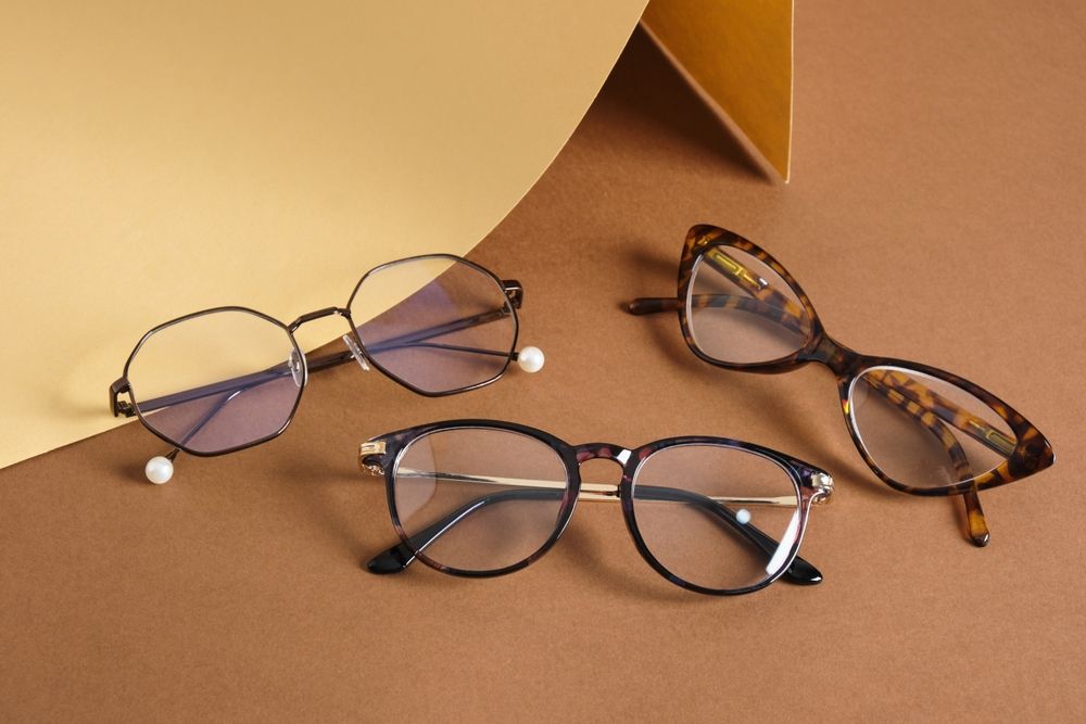 Three pairs of eyeglasses on tan and brown geometric background