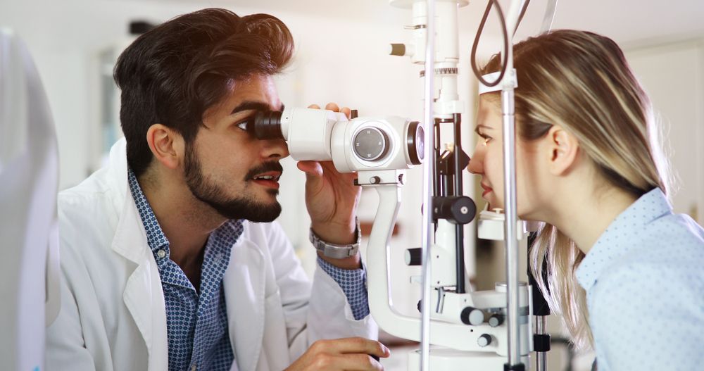 Optometrist and patient using a slit lamp eye exam in a clinic