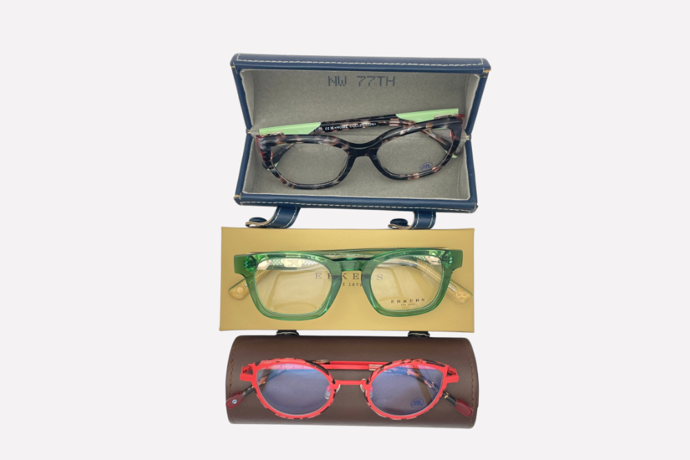 Three pairs of eyeglasses on a gray microfiber pouch