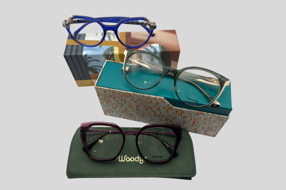 Four eyeglasses frames around a green Wooys case on a light background.