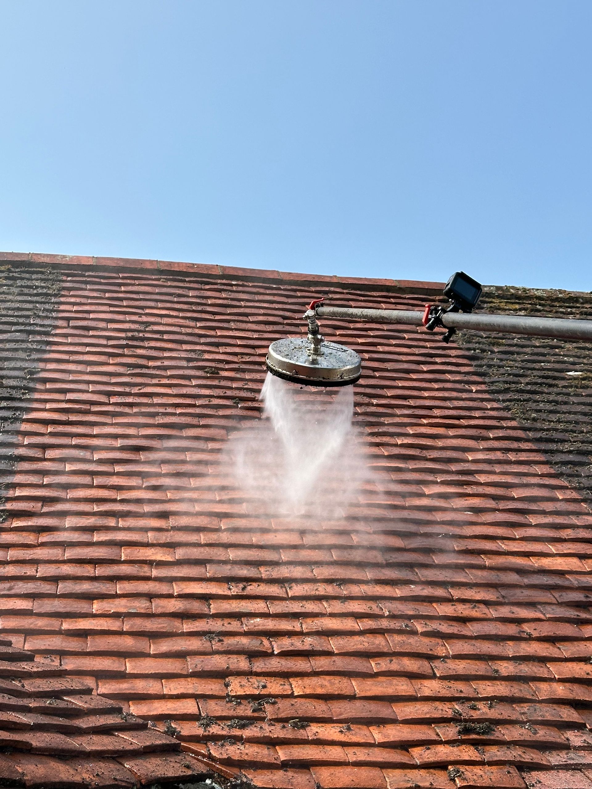 A man is using a high pressure washer to clean his driveway in front of his house.