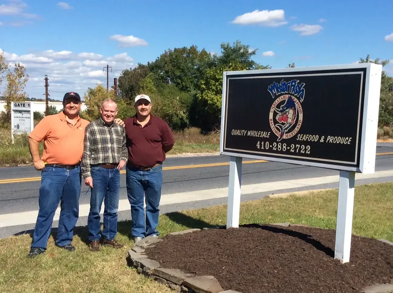 Three men standing in front of a sign that says waste management