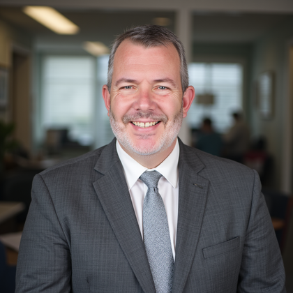 Man in gray suit smiling, in an office setting.